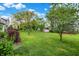 Large grassy backyard with mature trees and a storage shed, offering ample space for recreation and storage at 7156 Chemistry Ct, Indianapolis, IN 46239