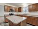 Kitchen with wood cabinets, stainless steel appliances, center island, gray countertops and wood-look flooring at 7156 Chemistry Ct, Indianapolis, IN 46239