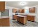 Spacious kitchen featuring wood cabinets, gray countertops, stainless steel appliances, and gray wood-look floors at 7156 Chemistry Ct, Indianapolis, IN 46239