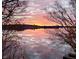 A serene sunset reflected on the lake, framed by silhouetted tree branches in the foreground at 7400 Oakbay Dr, Noblesville, IN 46062