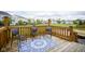 Wooden deck with three chairs, a blue patterned rug, and a view of the backyard and neighborhood at 7632 Nestucca Trl, Noblesville, IN 46062
