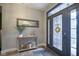 Inviting foyer with wood floors, console table, decorative mirror, and glass-paneled door at 7632 Nestucca Trl, Noblesville, IN 46062