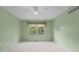 A bright bedroom featuring neutral carpet, soft green walls, and a window overlooking the backyard at 774 Chapel Pines W Dr, Indianapolis, IN 46234