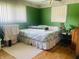 Green bedroom with natural light, wood floors and floral bedspread at 7844 Partridge Rd, Southport, IN 46227