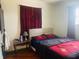 Bedroom featuring red curtains, wood floors and a comfortable bed at 7844 Partridge Rd, Southport, IN 46227