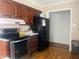 A practical kitchen features wood cabinets, a black refrigerator, and laminate countertops, creating a functional cooking space at 7844 Partridge Rd, Southport, IN 46227