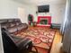 Cozy living room with a red brick fireplace, plush leather sofa, and a vibrant patterned rug on hardwood floors at 7844 Partridge Rd, Southport, IN 46227