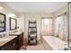 Bright bathroom featuring double sinks, a soaking tub, and decorative accents at 9915 Wellsford Cir, Indianapolis, IN 46236