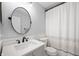 Bright bathroom features a modern vanity with round mirror and a shower with decorative curtain at 9915 Wellsford Cir, Indianapolis, IN 46236