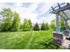 Landscaped backyard featuring a well-manicured lawn, pergola with stone supports, and select trees for added privacy at 10291 Normandy Way, Fishers, IN 46040