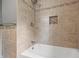 Beautiful bathroom with a white tub, shower, and beige tile surround with decorative tile border and inset at 10429 Lasalle Rd, Carmel, IN 46033