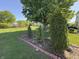 Landscaped backyard featuring a large grassy area, mature trees, and garden bed at 11163 Autumn Harvest Dr, Fishers, IN 46038