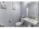 A clean half bathroom features a pedestal sink, toilet, and floral art at 1119 Albemarle Cir, Noblesville, IN 46062