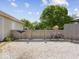 View of a gravel backyard with a wooden fence, small garden, and a classic bicycle, under a sunny sky at 116 E Railroad St, Fountaintown, IN 46130