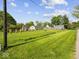 View of the house and the spacious green yard with fence, blue sky and telephone pole at 116 E Railroad St, Fountaintown, IN 46130