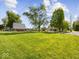 View of house exterior with large grassy lawn, trees, and red car parked in the drive at 116 E Railroad St, Fountaintown, IN 46130