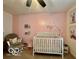 Charming Bedroom with pink accent wall, white crib, rocker and soft carpet at 1287 Northcraft Ct, Franklin, IN 46131