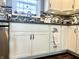 Close up of modern white cabinets, stainless steel appliances, and tiled backsplash in kitchen area. Large window at 135 Crestwood Ave, Crawfordsville, IN 47933