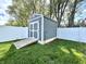 Backyard storage shed with ramp, painted in complementary grays, and surrounded by a white vinyl fence at 135 Crestwood Ave, Crawfordsville, IN 47933