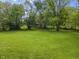 Lush, green backyard with mature trees and manicured lawn provides a serene outdoor space with fenced border at 13909 Springmill Rd, Carmel, IN 46032