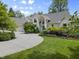 Charming brick home featuring a circular driveway, manicured lawn, and lush landscaping at 13909 Springmill Rd, Carmel, IN 46032