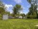 Expansive backyard with lush green grass, mature trees, storage shed, and plenty of space for outdoor activities at 1605 S Whittier Pl, Indianapolis, IN 46203