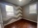 Bedroom showcasing a chevron-patterned accent wall, hardwood flooring, and a large window at 1605 S Whittier Pl, Indianapolis, IN 46203