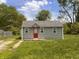 Charming single-story home featuring a red front door and freshly painted exterior in a serene, green yard at 1605 S Whittier Pl, Indianapolis, IN 46203