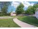 A spacious backyard with lush grass, a charming shed, a gravel parking area, and a paved walkway at 2025 E Broadway St, Fortville, IN 46040