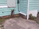 Shows the exterior of a home with turquoise wood siding, a concrete foundation, and overgrown landscaping at 2134 Dr Andrew J Brown Ave, Indianapolis, IN 46202