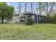 View of the house showcasing the blue painted siding, lush green yard, and mature trees at 2344 N Leland Ave, Indianapolis, IN 46218
