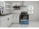 Kitchen featuring a stainless steel microwave, stove, white cabinets, and granite countertops at 2344 N Leland Ave, Indianapolis, IN 46218