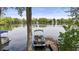 Scenic lake view with a modern pontoon boat docked and surrounded by lush trees and beautiful homes at 3602 Bay Rd S Dr, Indianapolis, IN 46240
