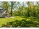 The property includes a lush green yard, a fire pit, and outbuilding, with surrounding trees ensuring privacy and a natural setting at 455 E Main St, Danville, IN 46122