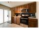 A kitchen with wood cabinets, stainless steel appliances, tile floors, and a stainless steel refrigerator at 506 S Green St, Brownsburg, IN 46112