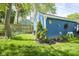 Backyard view showcasing a delightful blue-painted garage adorned with whimsical flower decorations and lush greenery at 5119 Ralston Ave, Indianapolis, IN 46205