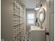 A stylish bathroom with a patterned shower curtain, unique flooring, and a round decorative mirror at 5119 Ralston Ave, Indianapolis, IN 46205