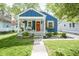 Charming blue home featuring a cozy front porch and a vibrant orange door, complemented by lush landscaping at 5119 Ralston Ave, Indianapolis, IN 46205