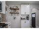 View of the kitchen with floating shelves, white cabinets, a coffee maker, and shiplap wall at 5119 Ralston Ave, Indianapolis, IN 46205