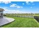 Large backyard featuring a stamped concrete patio, lush green lawn, and a black fence along the pond at 5248 Holborn Ave, McCordsville, IN 46055