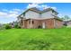 Green backyard with a brick house, garage and partial view of neighborhood at 5377 Crooked Stick Ct, Greenwood, IN 46142