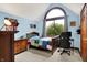 Cozy bedroom with an arched window, wooden furniture, and a dedicated workspace, blending comfort and functionality at 5377 Crooked Stick Ct, Greenwood, IN 46142