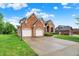 Well-maintained brick home with three-car garage, lovely landscaping, and a basketball hoop on the driveway at 5377 Crooked Stick Ct, Greenwood, IN 46142