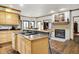 Open kitchen with island cooktop, adjacent fireplace and dining, and light wood cabinets at 5377 Crooked Stick Ct, Greenwood, IN 46142