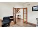 Well-lit home office with wood floors, French doors, a desk area and view of an ornate staircase at 5377 Crooked Stick Ct, Greenwood, IN 46142