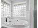 Bathroom features a garden tub with black faucet, glass-blocked windows providing ample natural light at 5601 W Sun Point Dr, Muncie, IN 47304