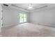 Bright main bedroom with tray ceiling, fan, neutral carpet, and sliding glass door to deck at 5601 W Sun Point Dr, Muncie, IN 47304