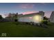 Backyard at dusk highlighting green lawn, landscaping, and outdoor patio at 5893 Crosscut Ln, Noblesville, IN 46062