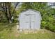 Weathered storage shed with double doors in a yard with green foliage, with some statuary by the entry at 5938 Dunseth Ct, Indianapolis, IN 46254