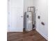 Utility room with light grey water heater, crisp white walls, and white paneled door with warm wood look flooring at 5938 Dunseth Ct, Indianapolis, IN 46254
